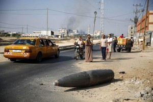 Palestinians look at an unexploded Israeli shell that landed on the main road outside the town of Deir Al-Balah in the central Gaza Strip